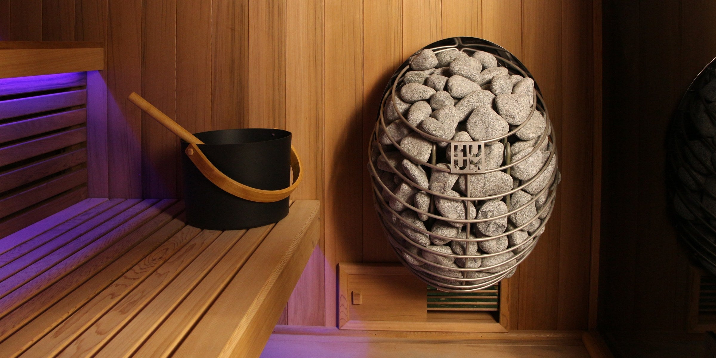 Traditional Steam Saunas — HUUM heater with cedar bench and ambient lighting