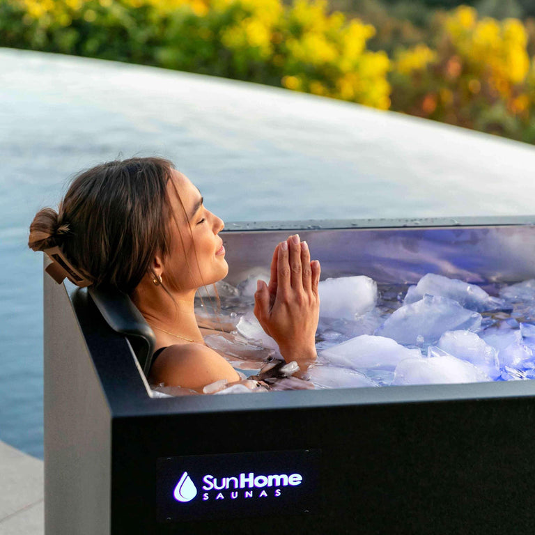 Sun Home Cold Plunge Pro filled with ice, outdoors beside greenery