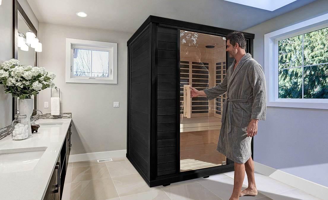 Person in a robe stepping into an indoor Sun Home far-infrared sauna in a bright home bathroom