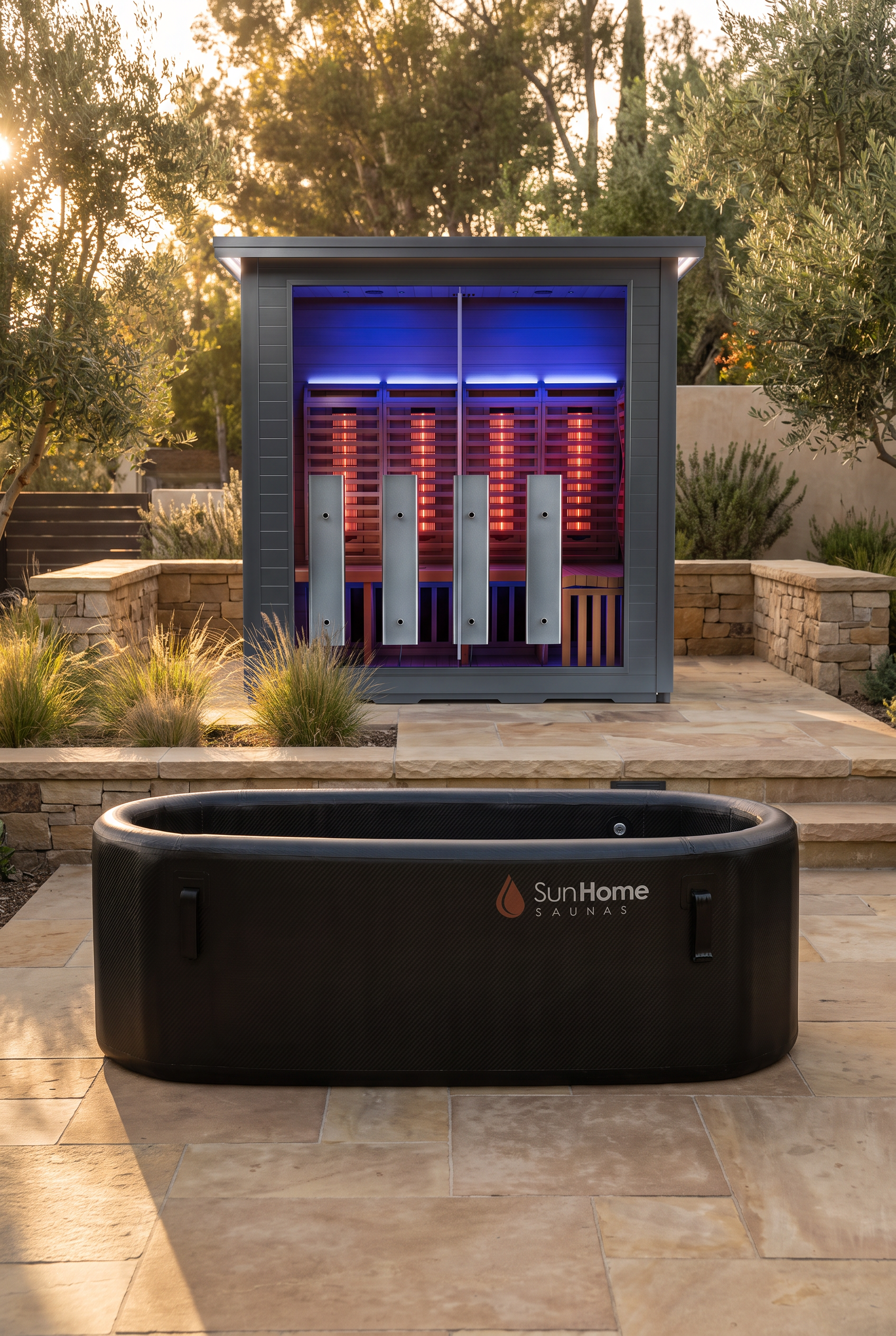 Black Sun Home inflatable cold plunge tub on a stone patio in front of a Sun Home outdoor sauna, its interior lit with red light panels