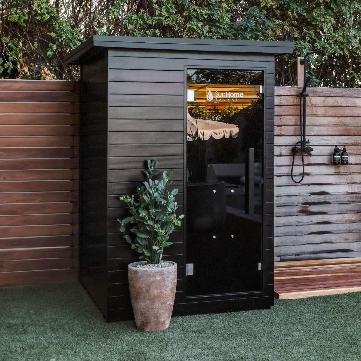 Sun Home Luminar outdoor sauna installed in a private backyard with wood fence and greenery