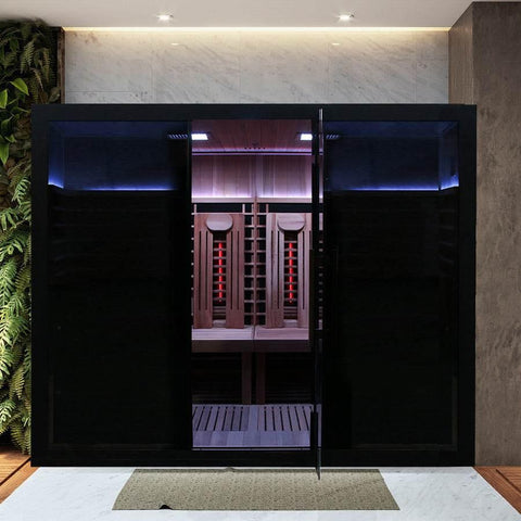 Sun Home Eclipse 4-person red light infrared sauna with black glass front beside a green plant wall