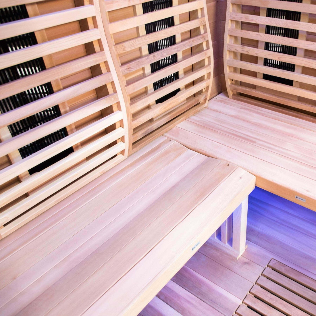 Close-up of the L-shaped Canadian red cedar bench and far-infrared heater panels inside the Sun Home Luminar 2-person sauna