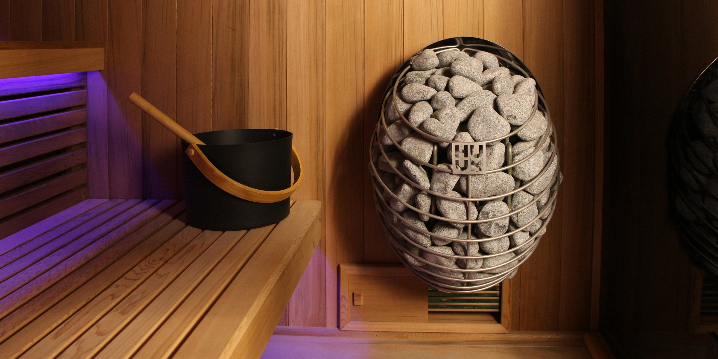 Traditional Steam Saunas — HUUM heater with cedar bench and ambient lighting